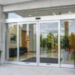 Automatic sliding doors with a directory board beside it.