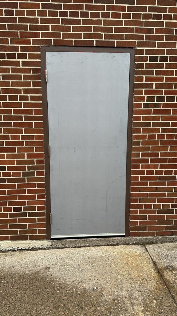 Silver metal door with brick wall